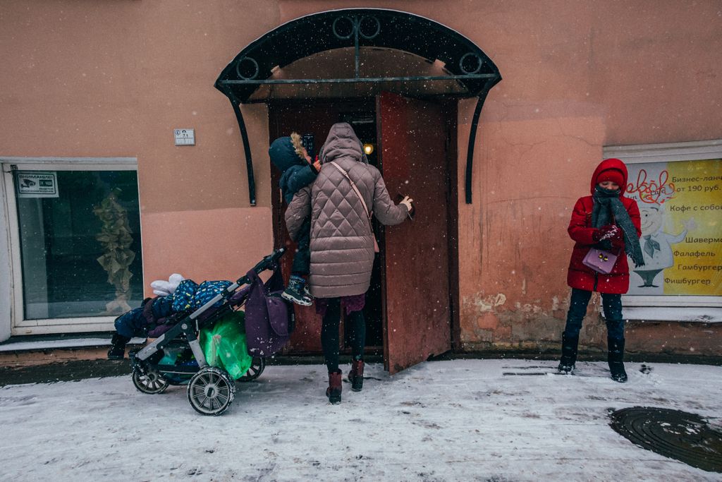 «Счастливая безысходность». Фоторепортаж о жизни многодетной семьи в петербургской коммуналке, Екатерина оставляет коляску у подъезда, забирая Давида на руках — discours.io