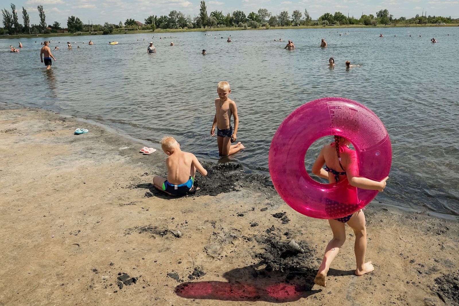 Дети играют на пляже в Славянске, 22 июня 2024 года. Украинским войскам удается удерживать этот город под своим контролем уже более десяти лет после того, как весной 2014-го в Славянск вошли (и были выбиты оттуда спустя несколько дней) отряды «добров