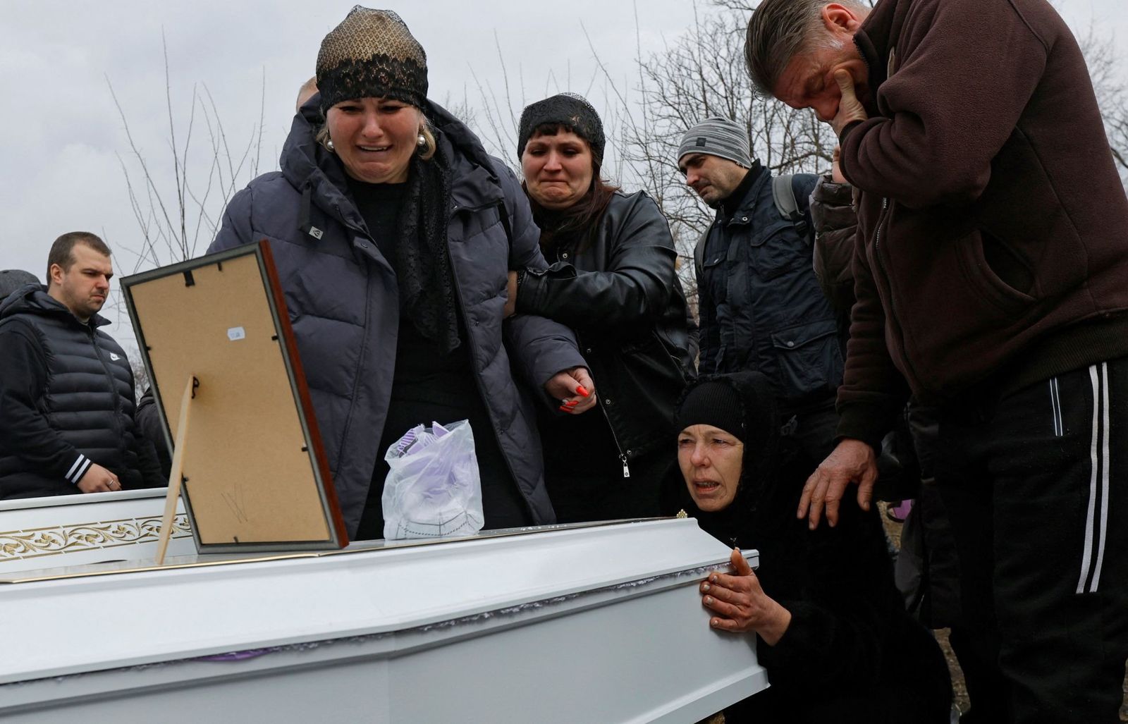 Бабушка и мать в окружении близких хоронят своих детей, погибших во время ракетного удара в Донецке. 18 марта / Alexander Ermochenko / Reuters / Scanpix / LETA