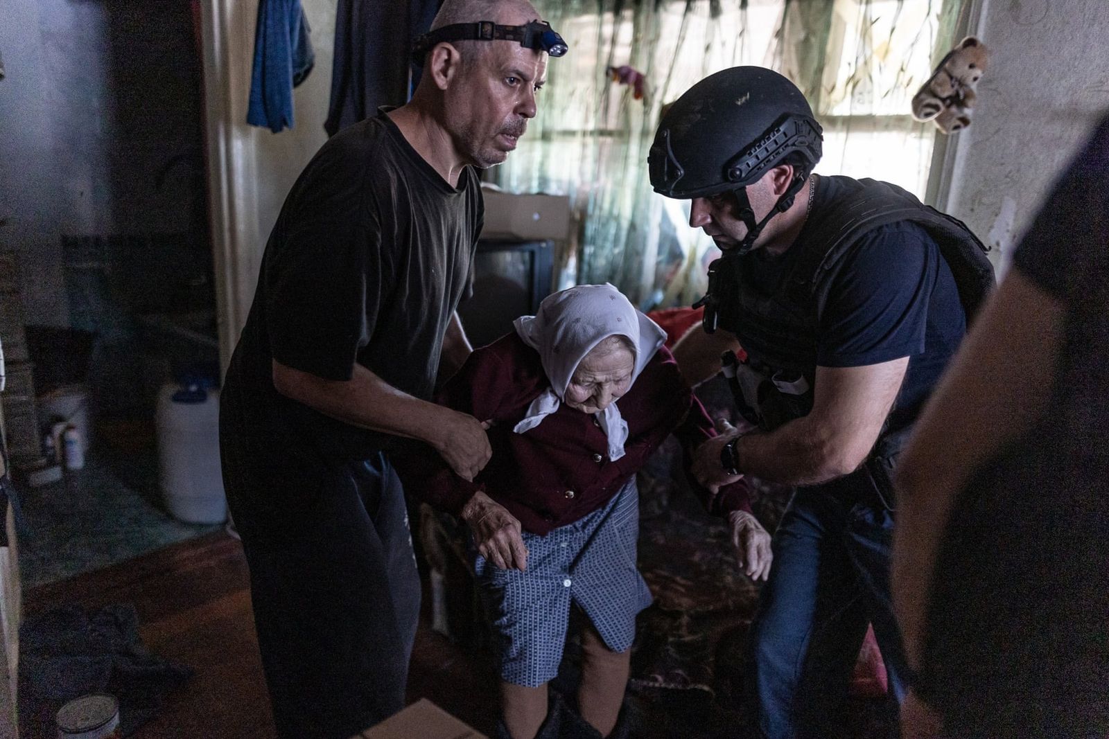 Украинский спасатель и члены семьи помогают 96-летней Валентине покинуть свой дом во время эвакуации из города Торецка. 30 июля / Anadolu / Getty Images