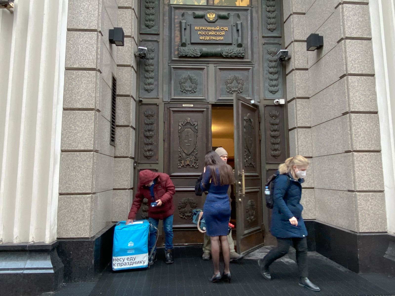 У служебного входа в Верховный суд можно было наблюдать комичную картину: работница суда встречает курьера, на сумке которого написано «Несу еду к празднику» / Костя Сиденко У служебного входа в Верховный суд можно было наблюдать комичную картину: работница суда встречает курьера, на сумке которого написано «Несу еду к празднику» / Костя Сиденко
