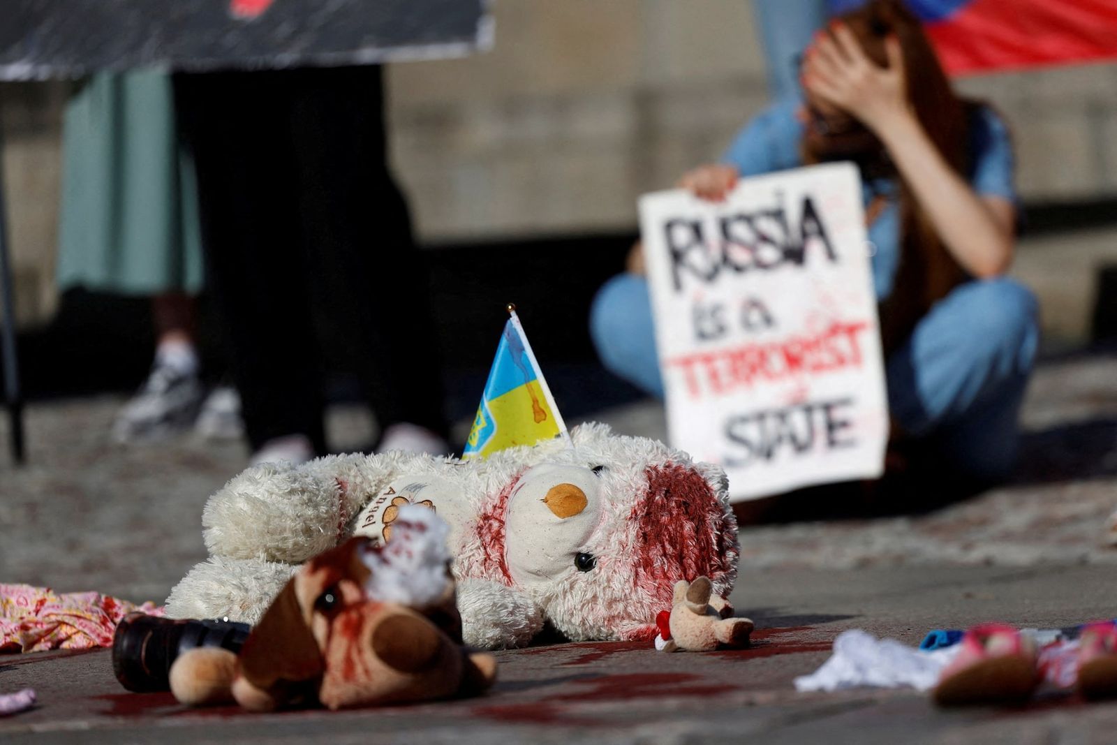 Плюшевый мишка с украинским флагом в инсталляции во время митинга в Праге, осуждающего российское нападение на детскую больницу в Киеве. 9 июля / David W Cerny / REUTERS