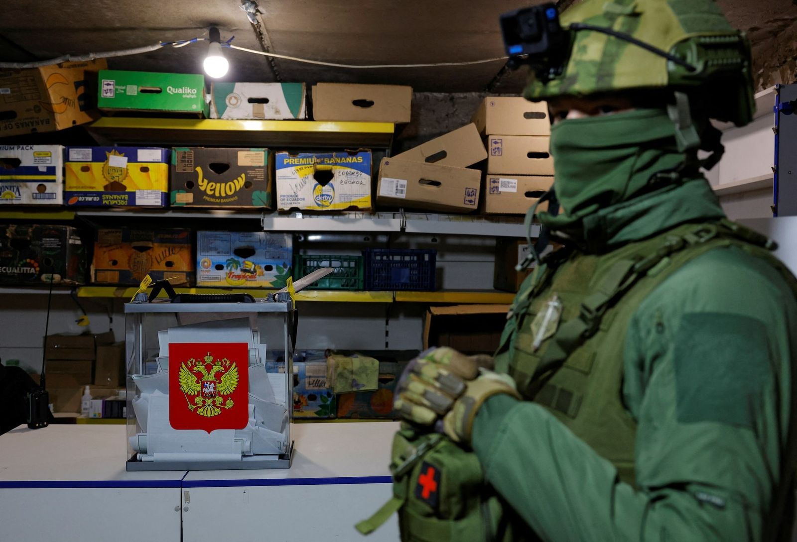 Военный стоит рядом с переносной урной для голосования в подвале разрушенного жилого дома во время выборов президента России в Авдеевке, Донецкой области. 16 марта / Alexander Ermochenko / REUTERS