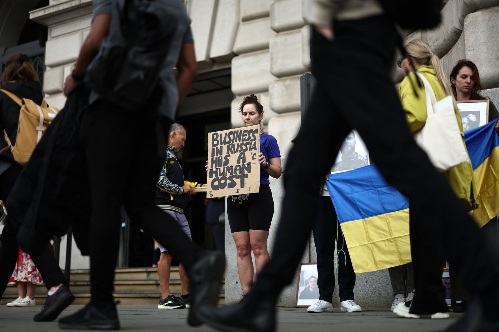Украинские беженцы собираются с фотографиями родственников и друзей, которые были убиты или ранены в Украине во время акции протеста возле штаб-квартиры Unilever, чтобы подчеркнуть продолжающуюся деятельность компании в России. Компания производит та