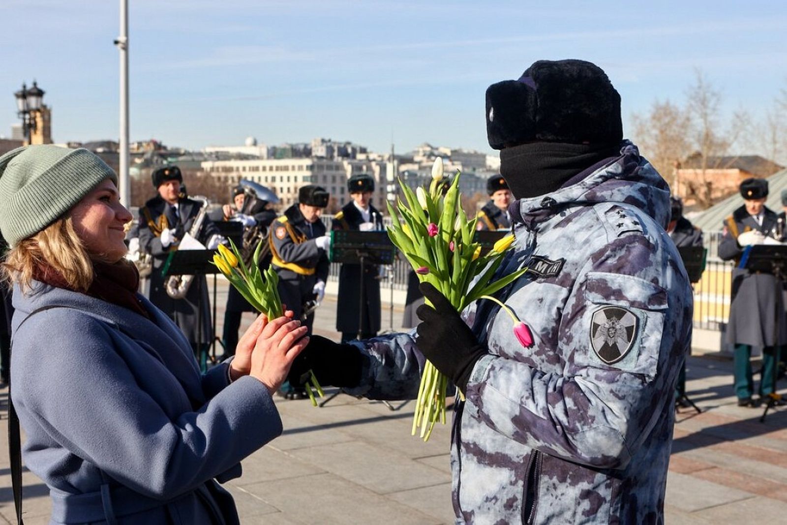 Сотрудники Росгвардии проводят в центре Москвы акцию, приуроченную к Международному женскому дню. На Патриаршем мосту возле храма Христа Спасителя выступает военный оркестр, в это же время мужчины в балаклавах и форме ОМОНа дарят проходящим мимо женщ