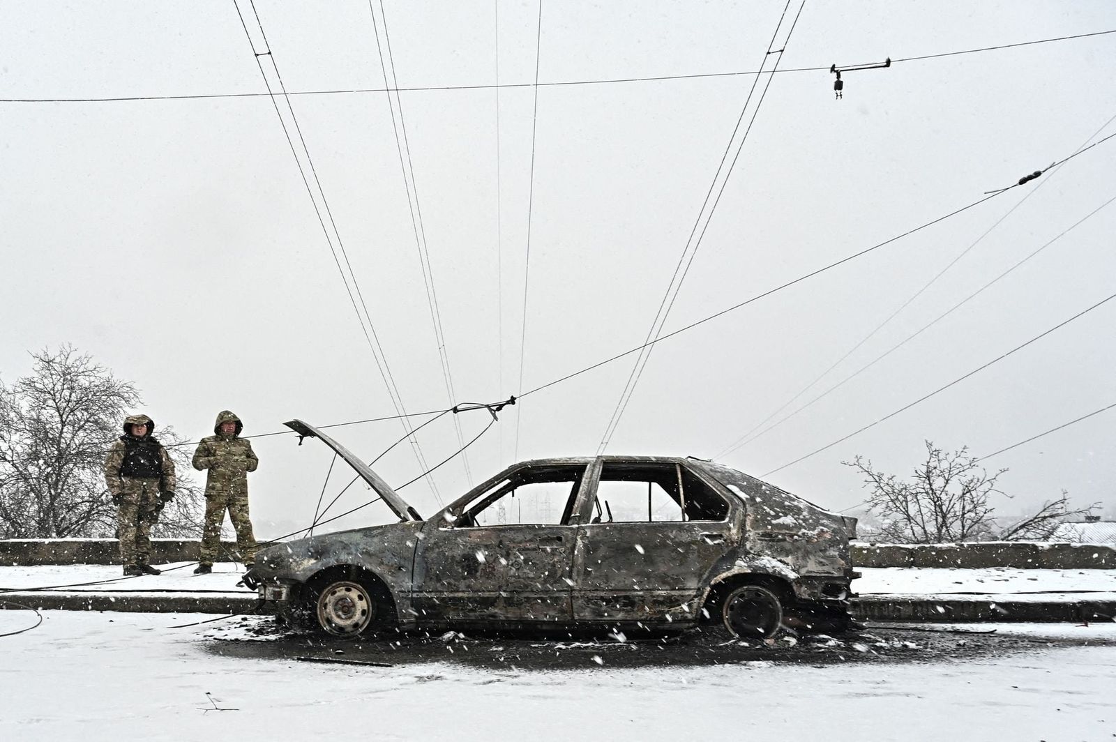 Военные следователи стоят рядом с разрушенными от обстрела автомобилями в Запорожье. 9 января / Reuters