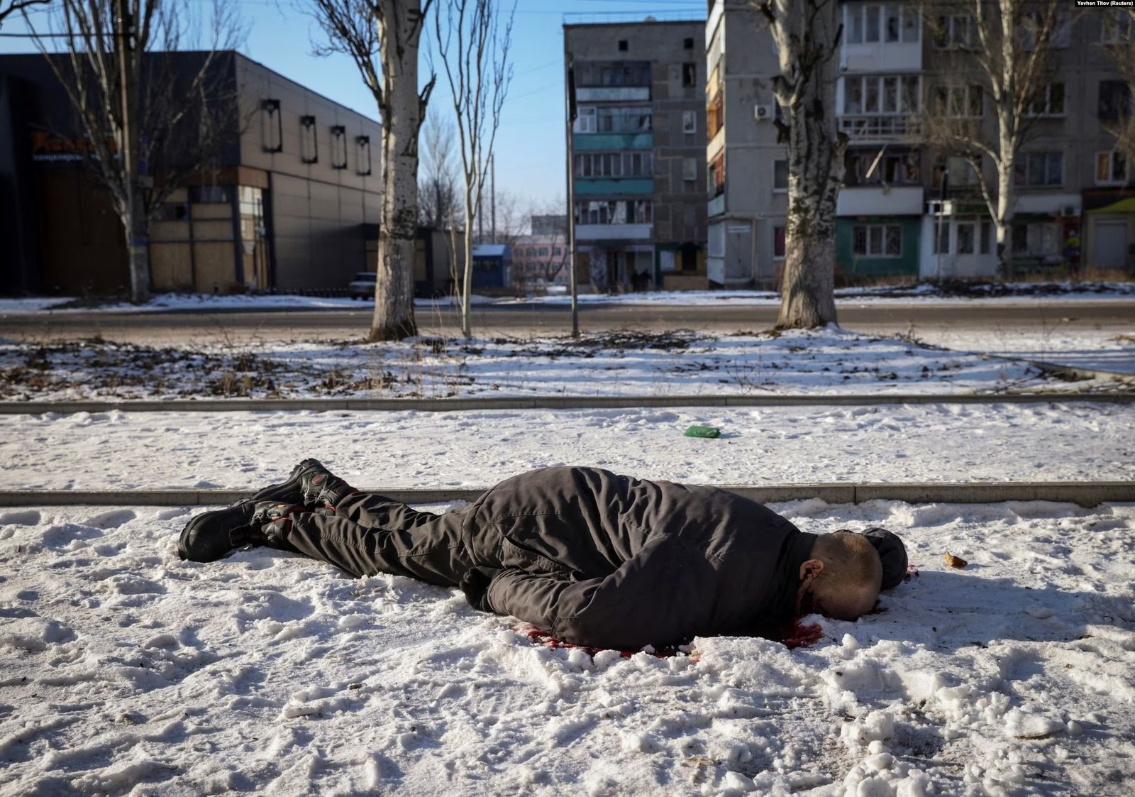 Тело местного жителя, убитого во время вторжения России в Украину, лежит на пустой улице прифронтового города Бахмут. 11 февраля  / Yevhen Titov / Reuters / RFL 