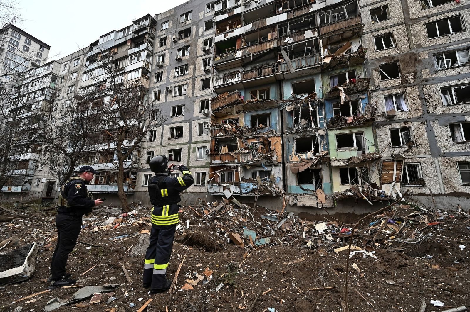 Спасатель фотографирует жилой дом, поврежденный в результате ракетного удара в Запорожье. 22 марта / Stringer / REUTERS
