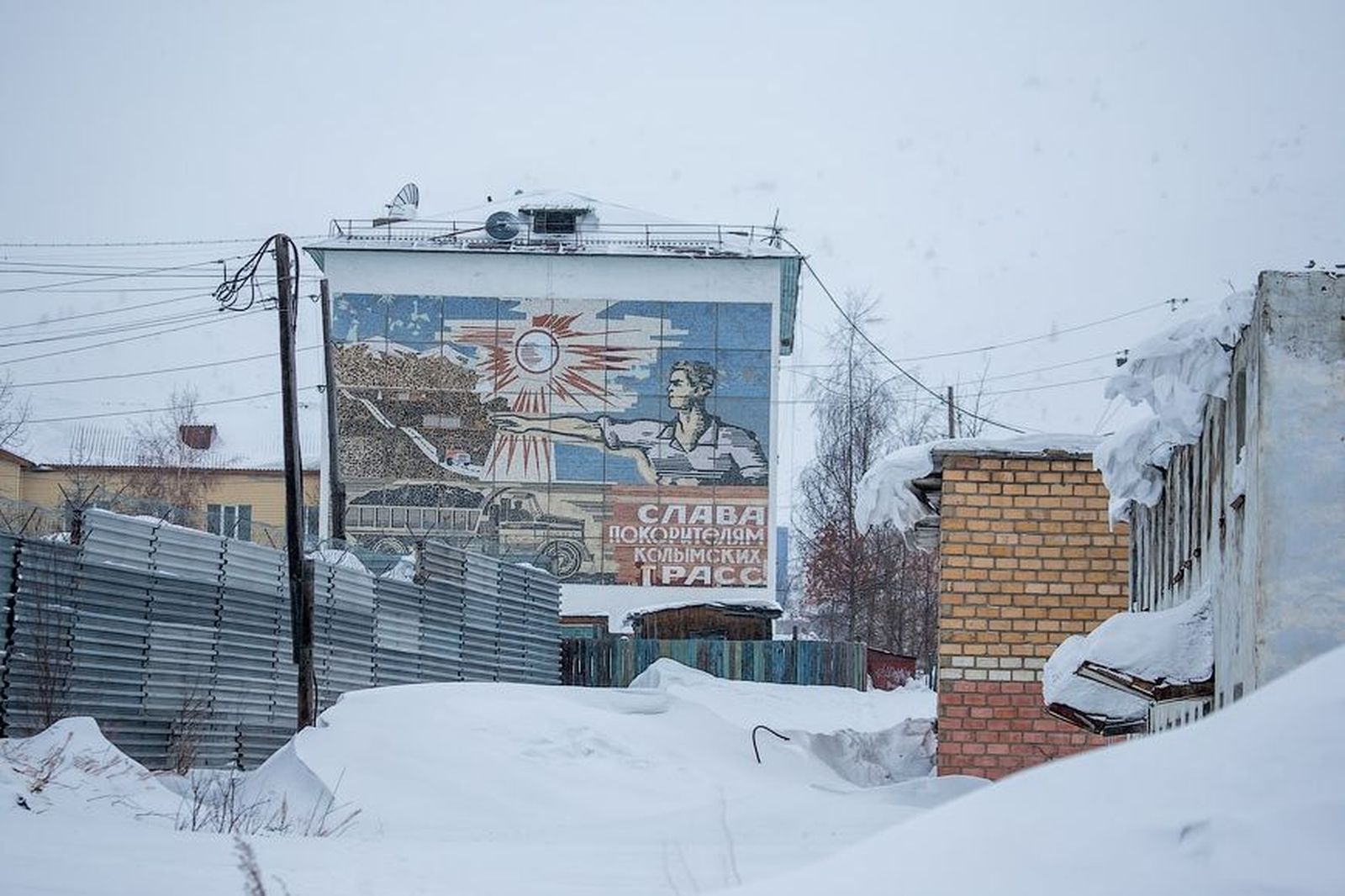 Панно «Слава покорителям колымских трасс» на стене жилого дома в поселке Омсукчан, Магаданская область / Фото: Сергей Анашкевич / За что в Магадане невзлюбили Юрия Дудя? Местные жители защищают свое прошлое — Discours.io