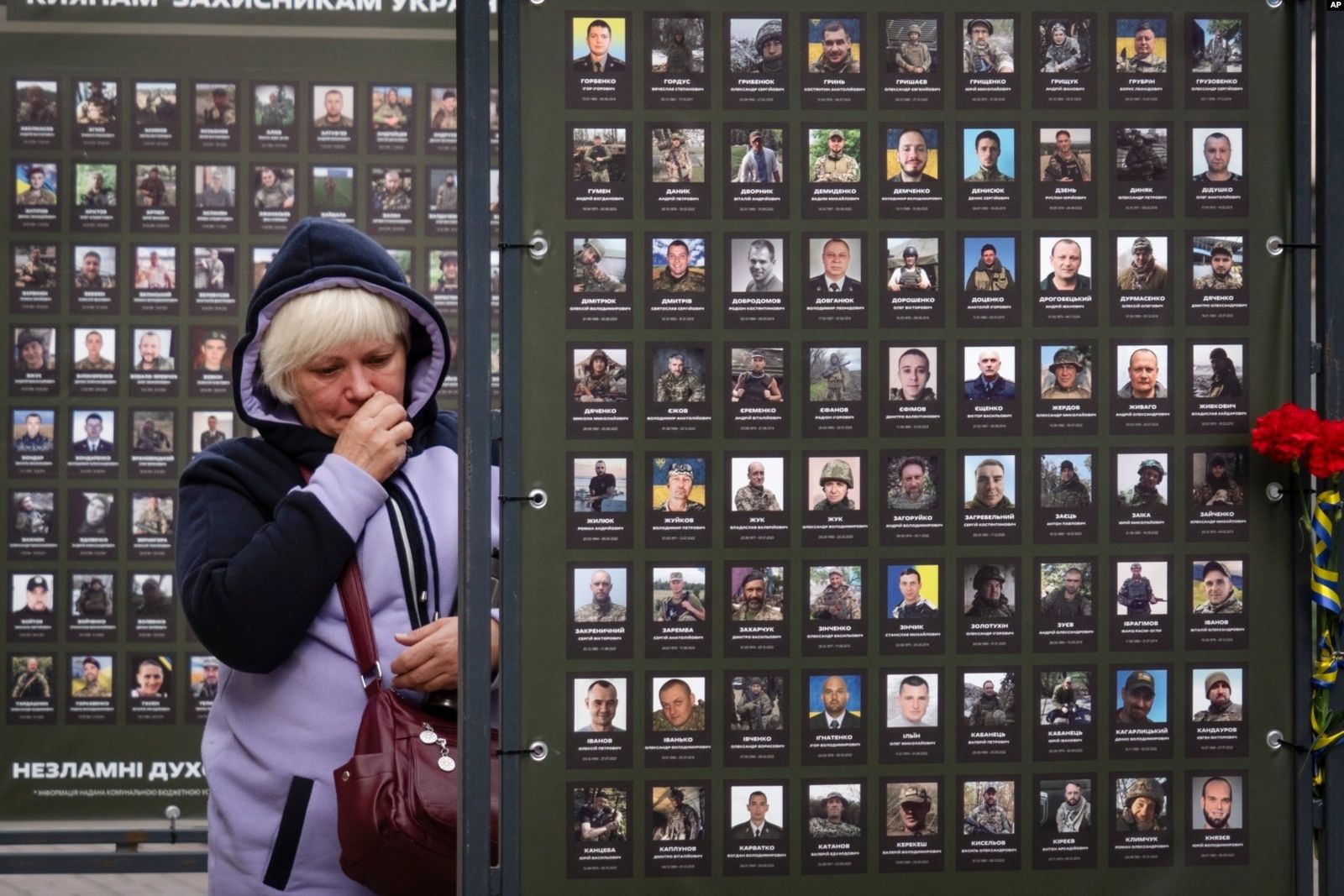 Людмила Мельник вытирает слезы, глядя на фотографию своего мужа Александра, погибшего в бою с российскими войсками, возле мэрии в Киеве. 4 октября / Efrem Lukatsky / AP Photo