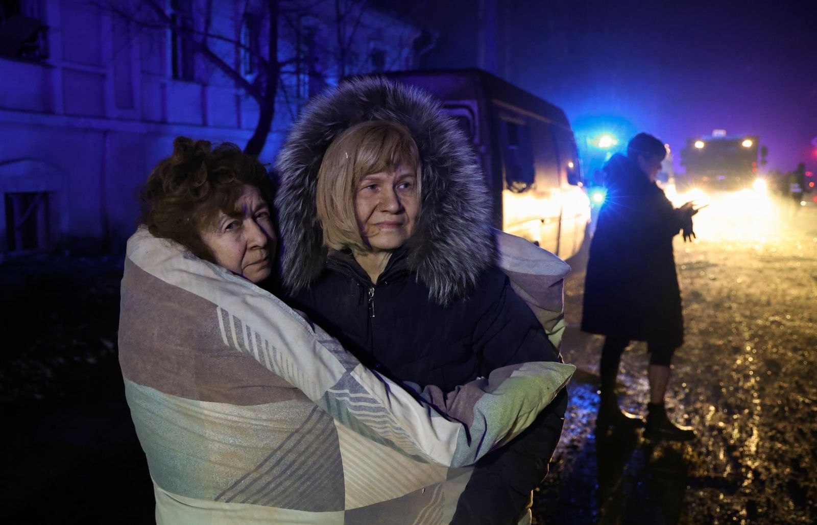 Женщины пытаются согреться на улицы после того, как они спаслись от российского обстрела. Две ракеты ударили по жилому району Харькова. Пострадали по меньшей мере 17 человек. 17 января / Yakiv Liashenko/EPA