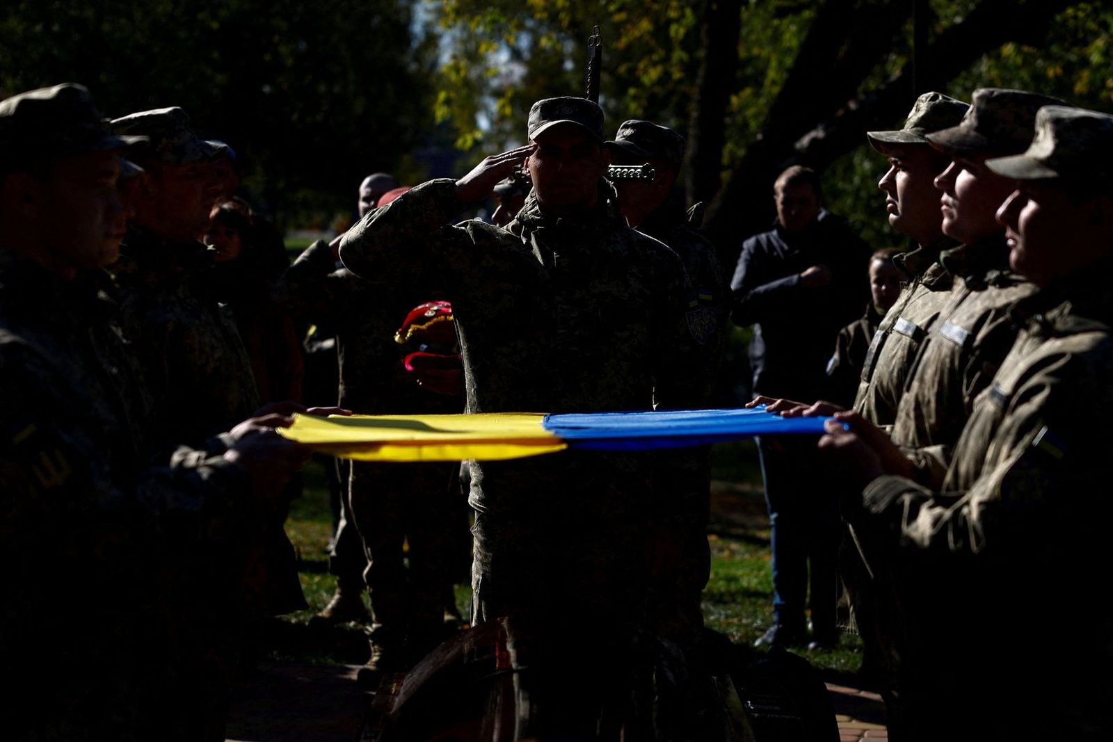 Украинские военнослужащие держат государственный флаг над гробом с телом своего соратника Виталия Баранова, командира батальона, погибшего в бою с российскими войсками в Донецкой области, во время похорон в селе Дымер Киевской области. 12 октября /  