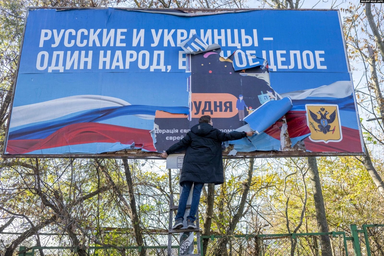 Мужчина снимает пророссийский баннер «Русские и украинцы — один народ, одно целое» в Херсоне после его освобождения. 14 ноября / Bulent Kilic / AFP / Radio Liberty 