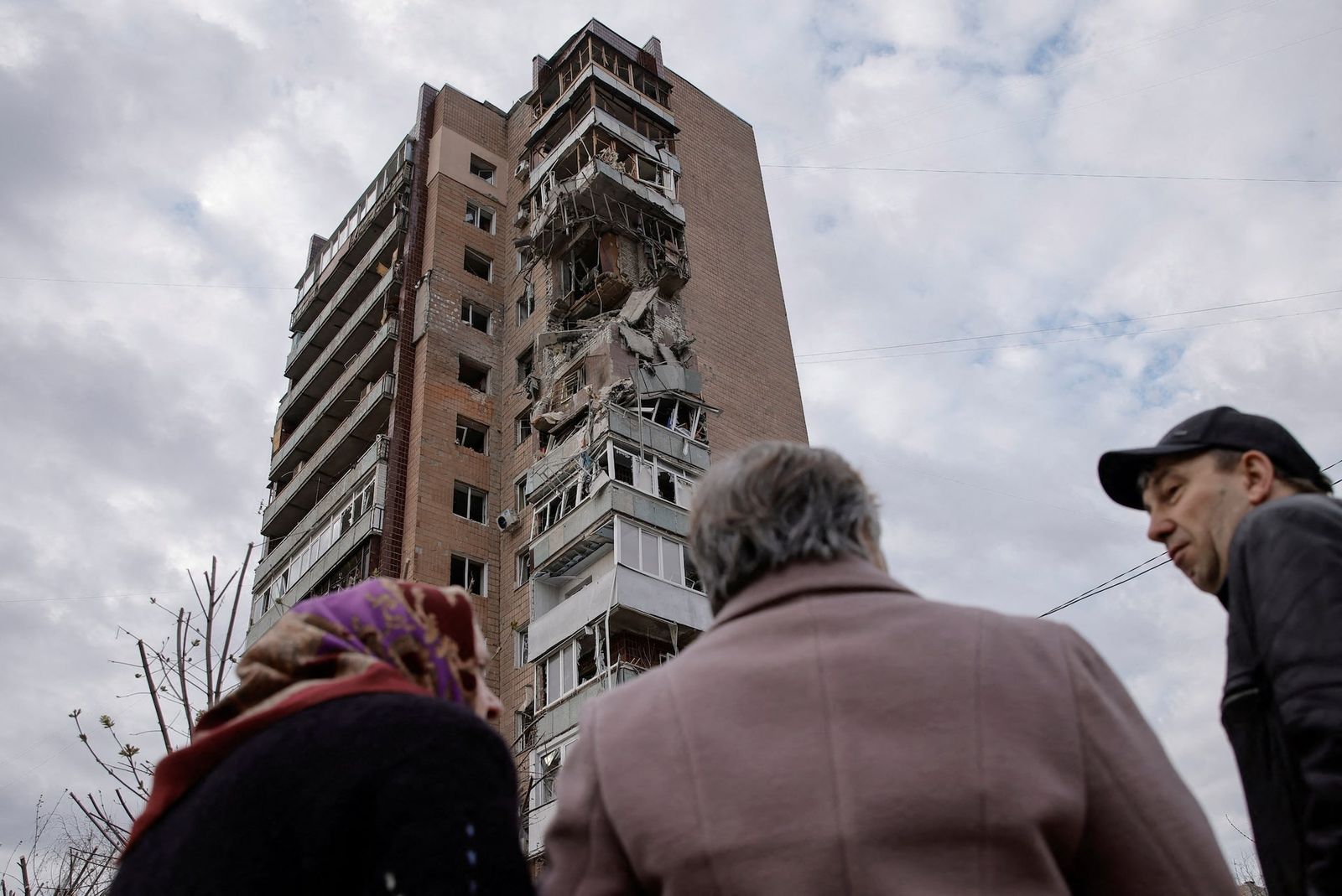 Мирные жители напротив многоэтажного жилого дома, поврежденного в результате атаки беспилотников в Харькове. 4 апреля / Yevhen Titov / REUTERS