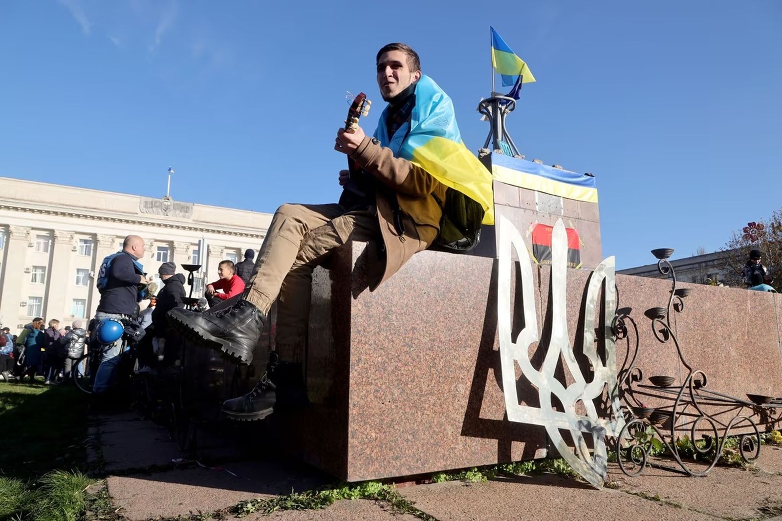Мужчина с украинским флагом играет на гитаре во время празднования освобождения Херсона. 14 ноября / Oleksandr Gimanov / AFP / Getty Images / Atlantic 